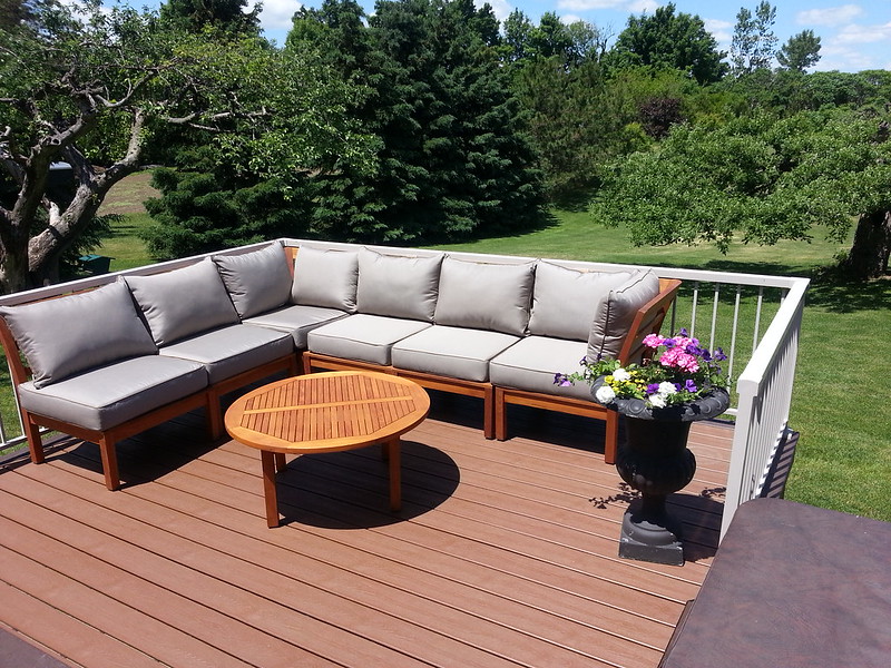 Oiled modular teak deep seating with grey cushions and a small round coffee table