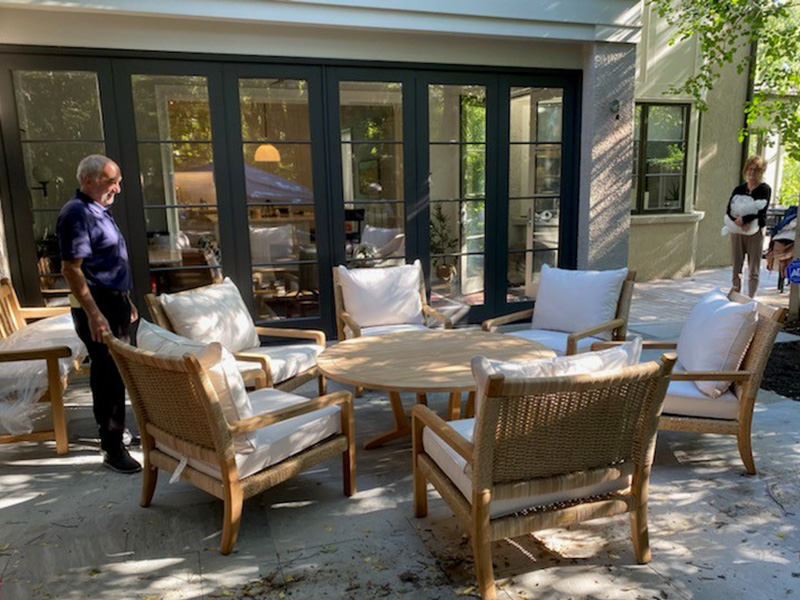 Light teak deep seating chairs with white cushions surrounding a low round coffee table
